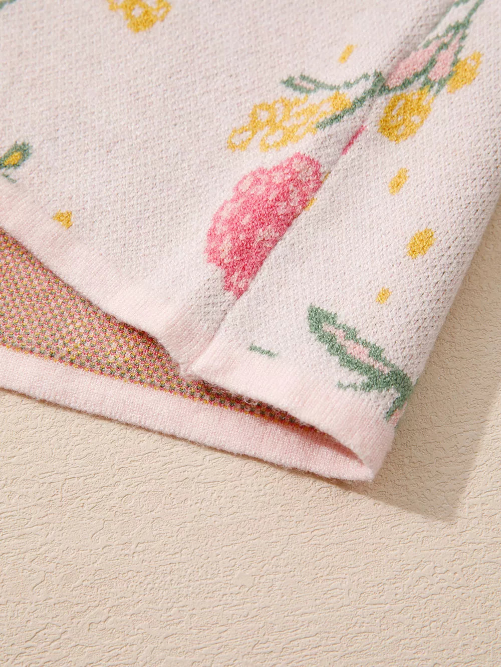 Floral V-neck knit sweater in light pink with yellow and green floral print.