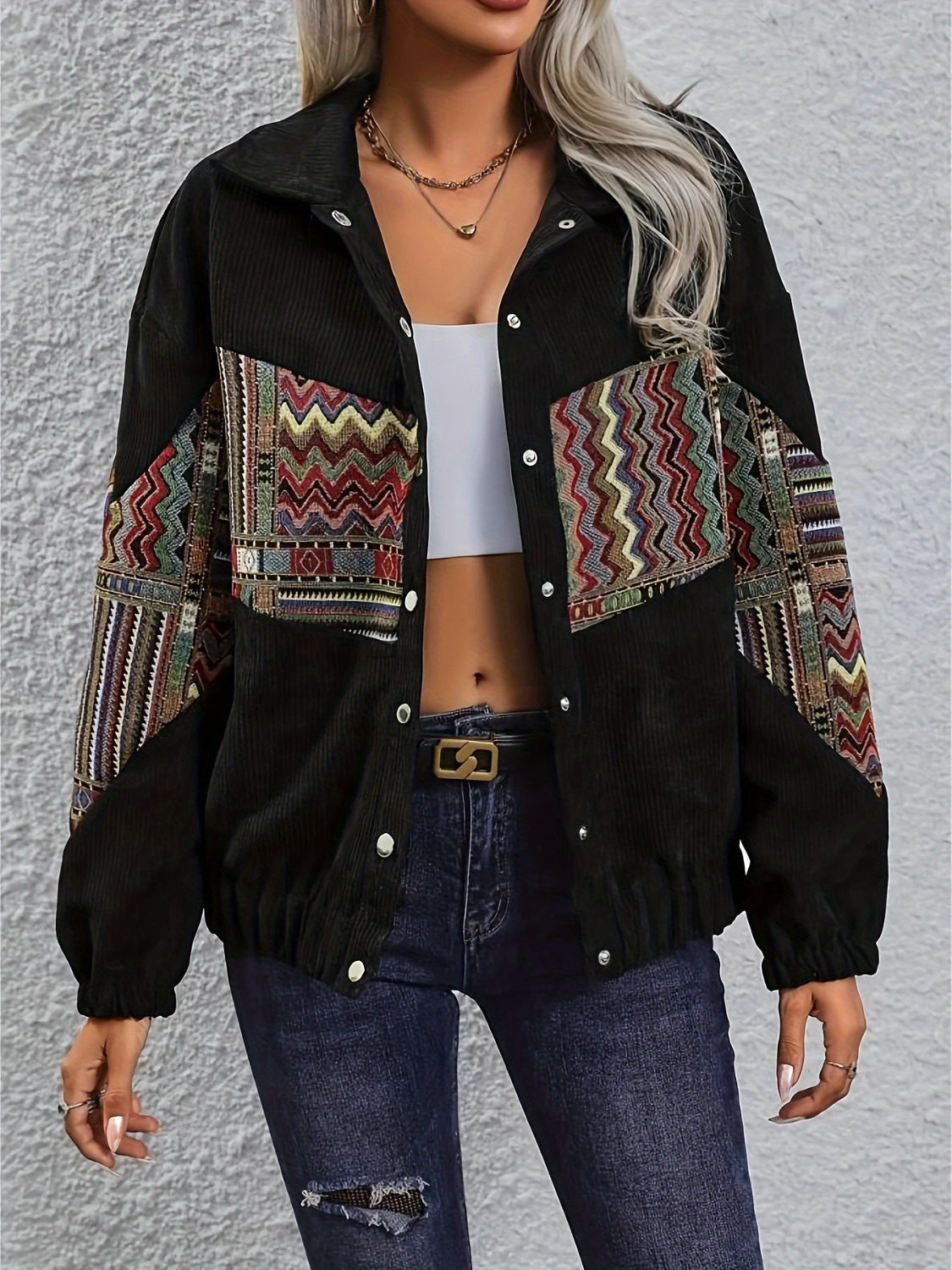 Black corduroy bomber jacket with colorful geometric patchwork on sleeves and chest.