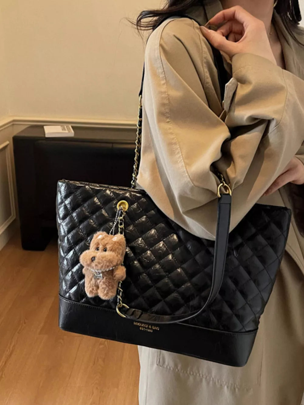 Black quilted shoulder bag with chain strap and teddy bear charm