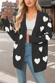 Black knit cardigan with white heart appliqué and buttons, styled with jeans.