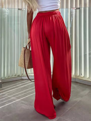 Red maternity pants with paperbag waist and wide legs, styled with a white top and straw bag.