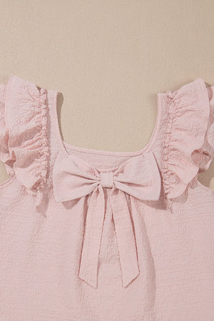 Blush pink textured blouse with ruffle sleeves and a large front bow detail.