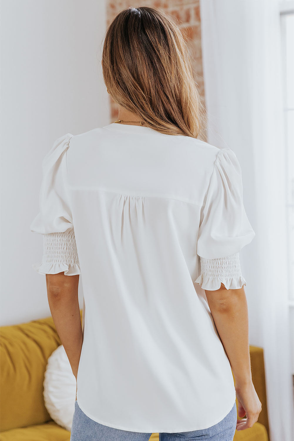 White puff sleeve blouse with smocking detail on sleeves and V-neck.