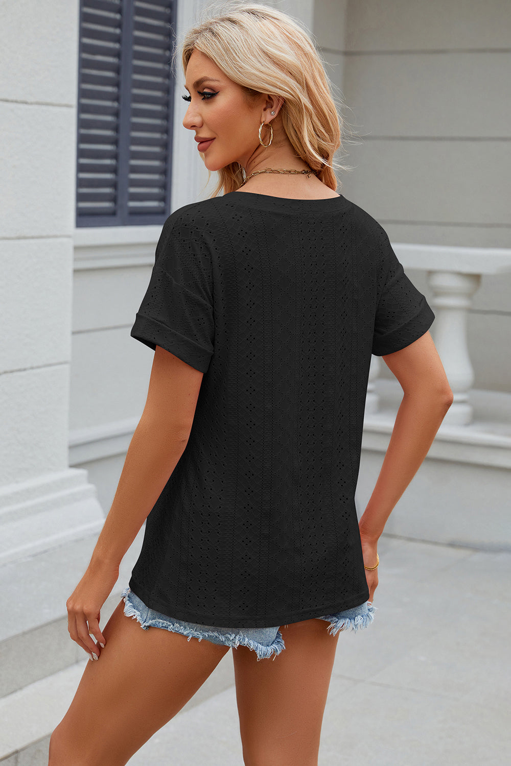 Black perforated tee with rolled sleeves and a casual fit.