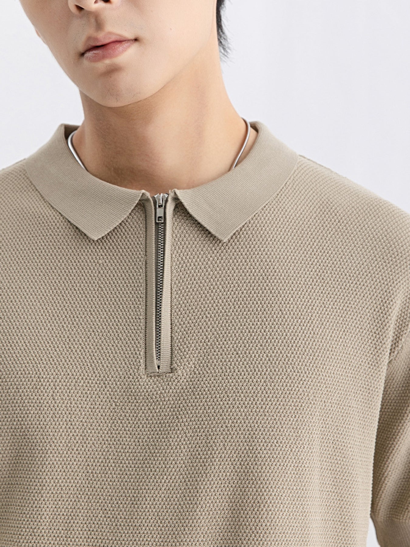 Textured knit zip-up polo shirt in apricot with a silver zipper and collar.