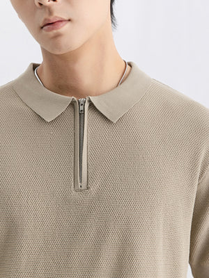 Textured knit zip-up polo shirt in apricot with a silver zipper and collar.