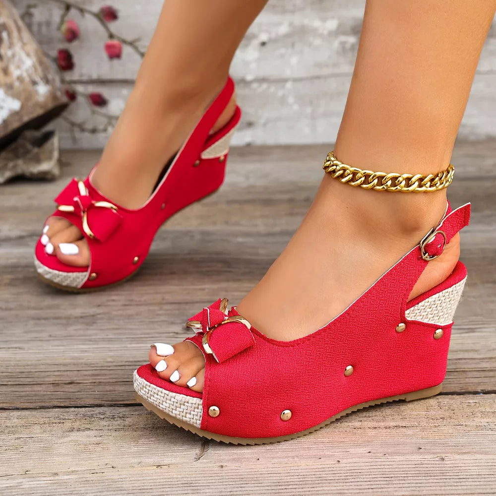 Red peep toe wedge sandals with decorative bow and adjustable strap.