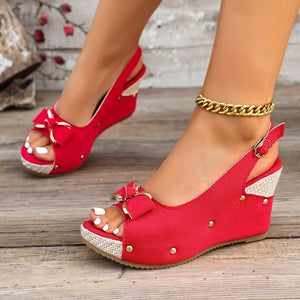 Red peep toe wedge sandals with decorative bow and adjustable strap.
