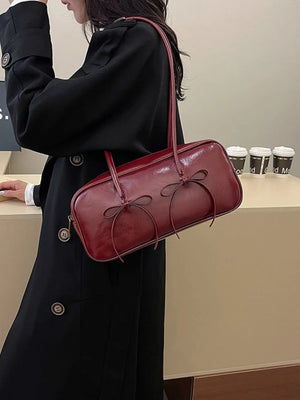 Burgundy patent leather shoulder bag with bow detail and thin straps.