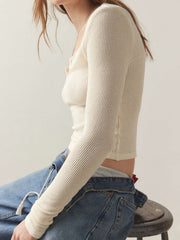 Cream ribbed crop top with square neckline and button detail, long sleeves.