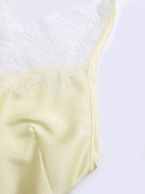 Yellow lace-trimmed satin slip dress with delicate lace detail on the neckline.