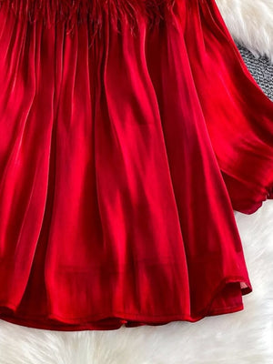 Red sheer blouse with feather trim and rhinestone embellishments.