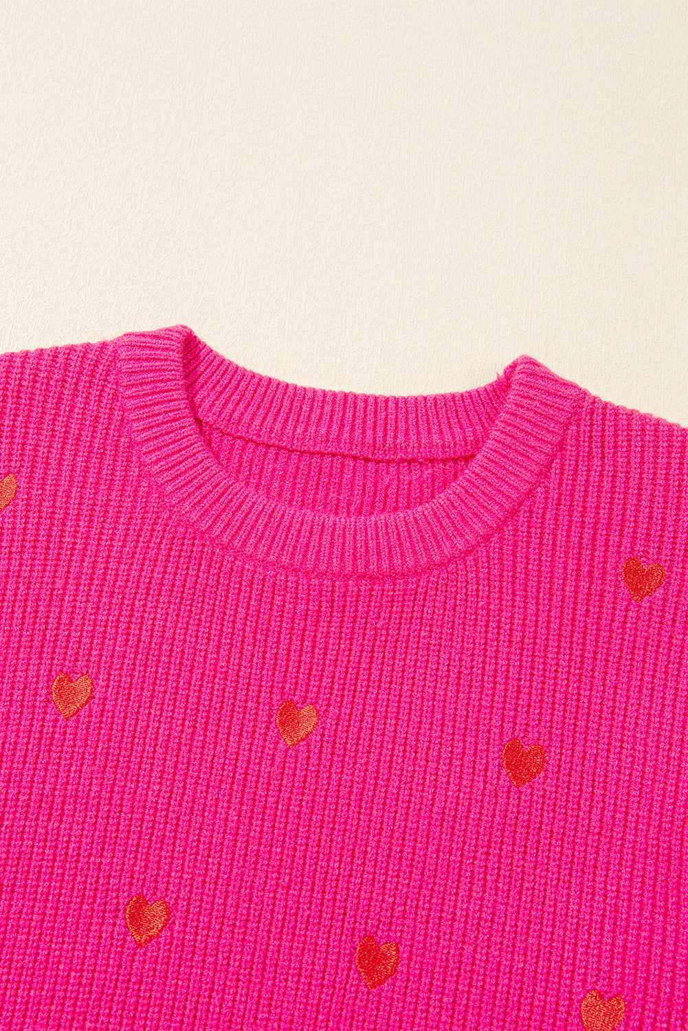 Pink ribbed crewneck sweater with embroidered red hearts, crew neck, long sleeves.