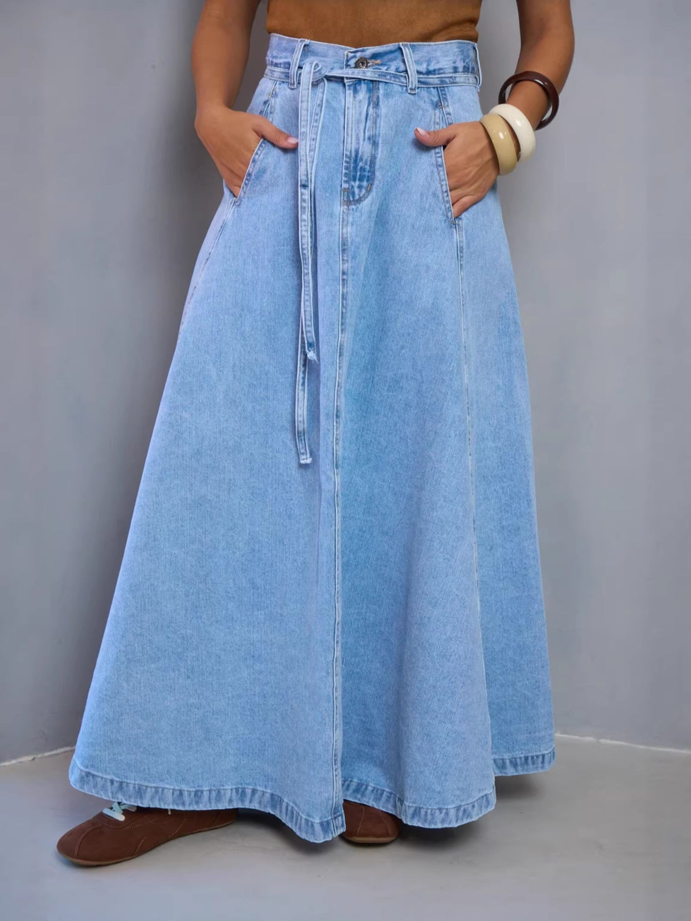 Light blue denim a-line maxi skirt with a tie waist and pockets.