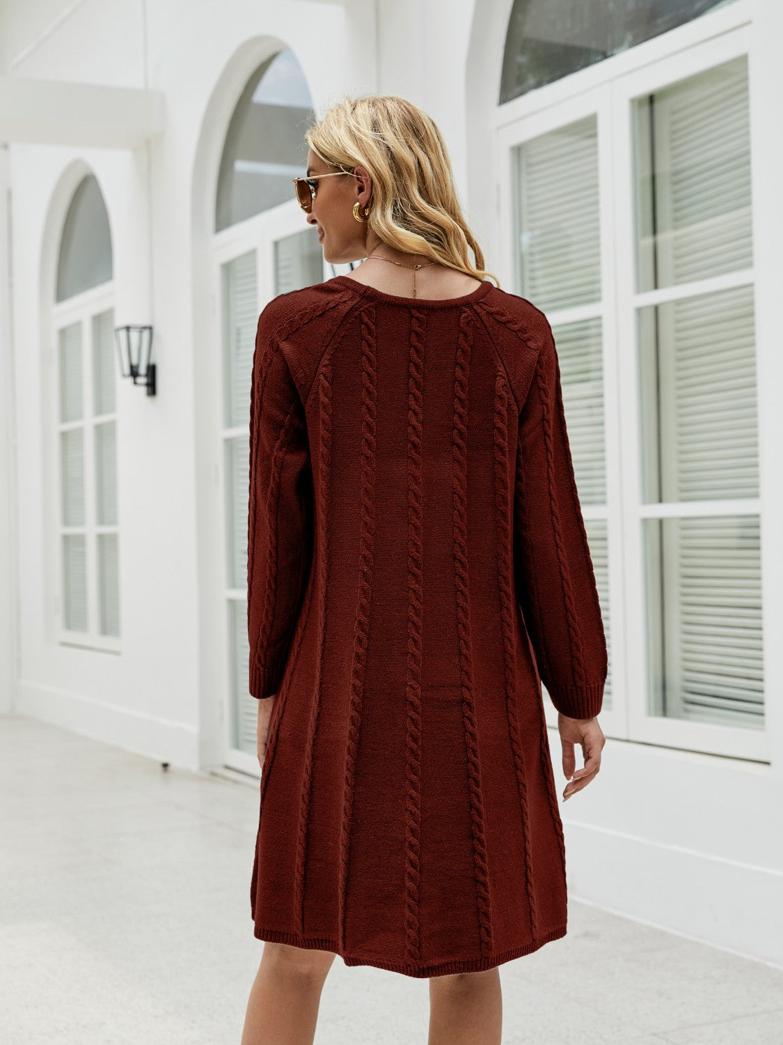Cable knit A-line sweater dress in wine with vertical cable details and long sleeves.