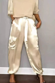 Beige satin two-piece ensemble with cargo pockets and a tie waist, styled with heels.