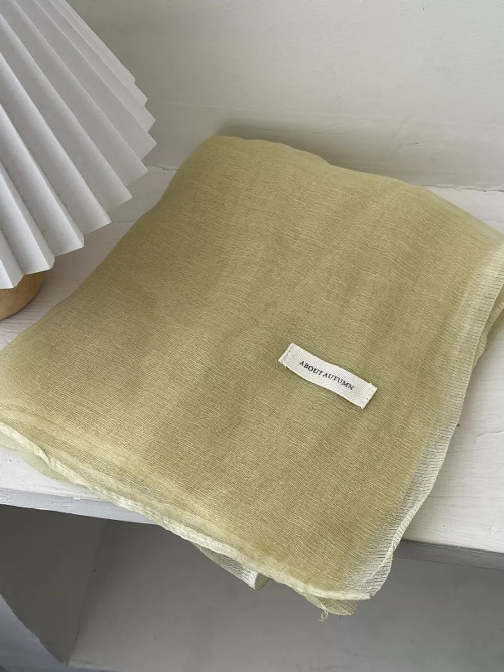 Delicate sheer polyester scarf in creamy yellow with a subtle crinkle texture.