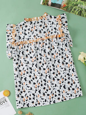 White blouse with terrazzo print, ruffle yoke, and short sleeves.
