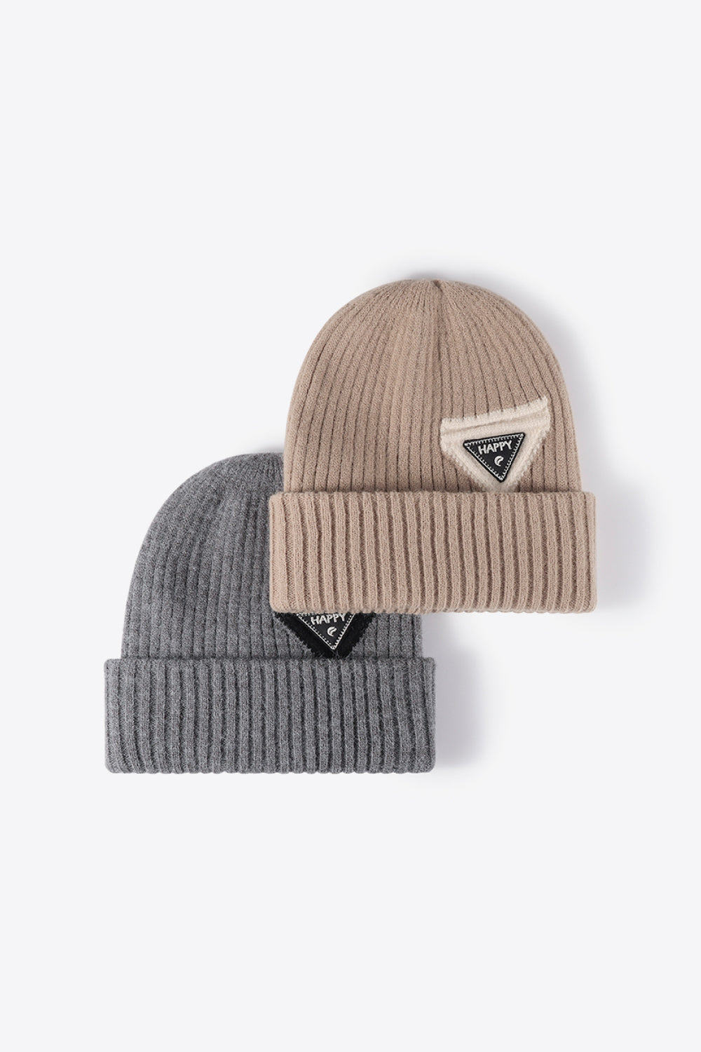 Ribbed acrylic beanies in beige and dark gray, each with a triangular "Happy" patch detail.