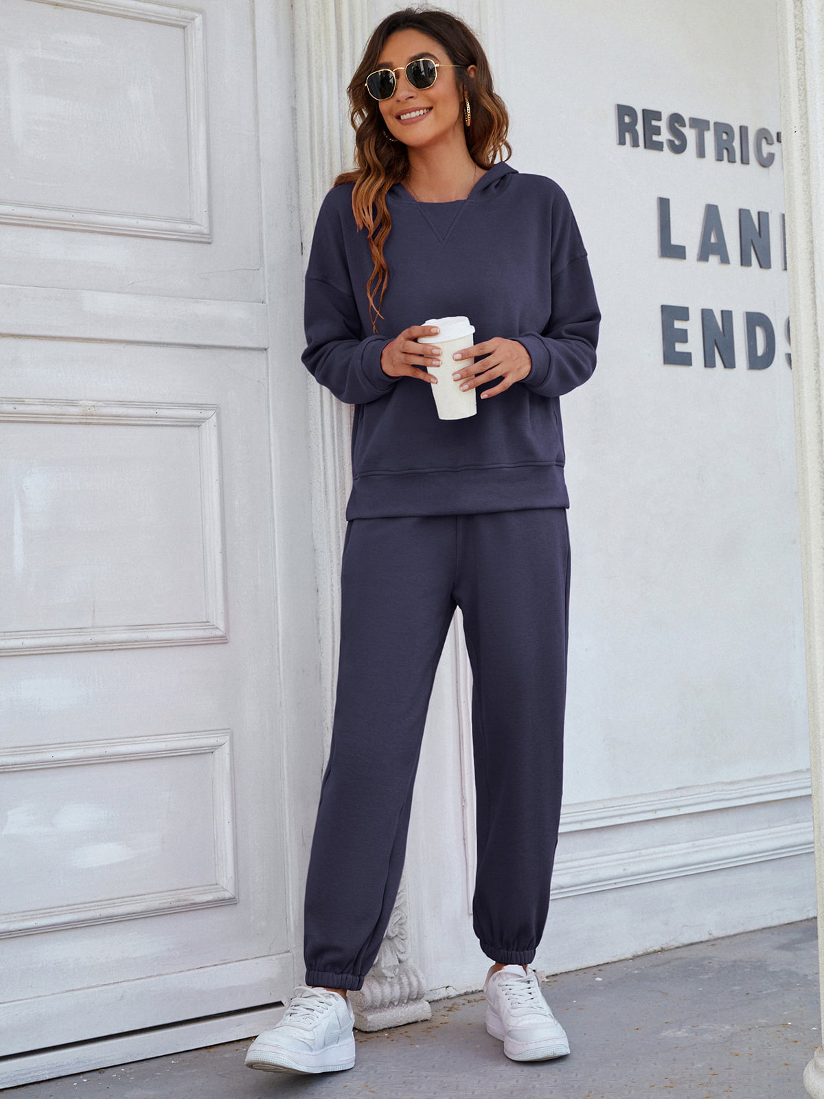 Dark blue joggers with cuffed ankles and a relaxed fit, styled with a matching hoodie and white sneakers.