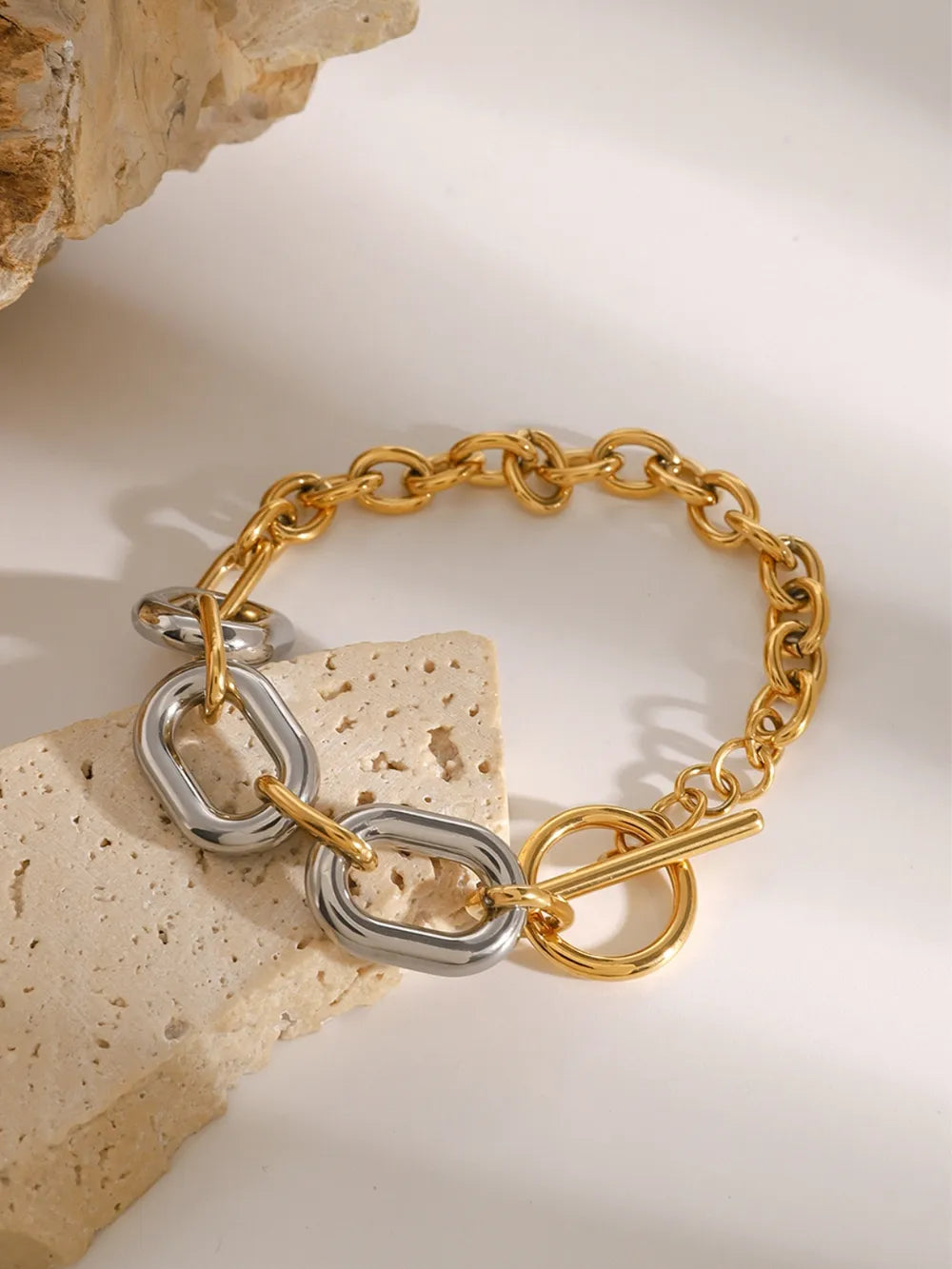 Two-tone chain link bracelet with toggle clasp and oval links in gold and silver tones.