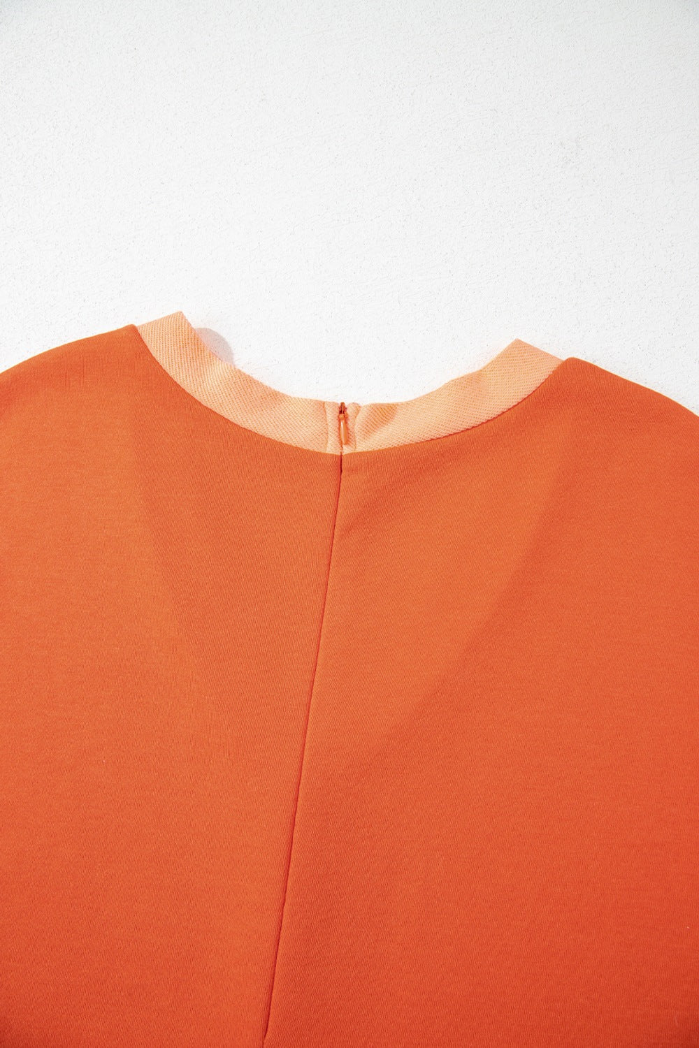 Orange colorblock romper with V-neck and zipper detail.