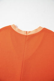 Orange colorblock romper with V-neck and zipper detail.