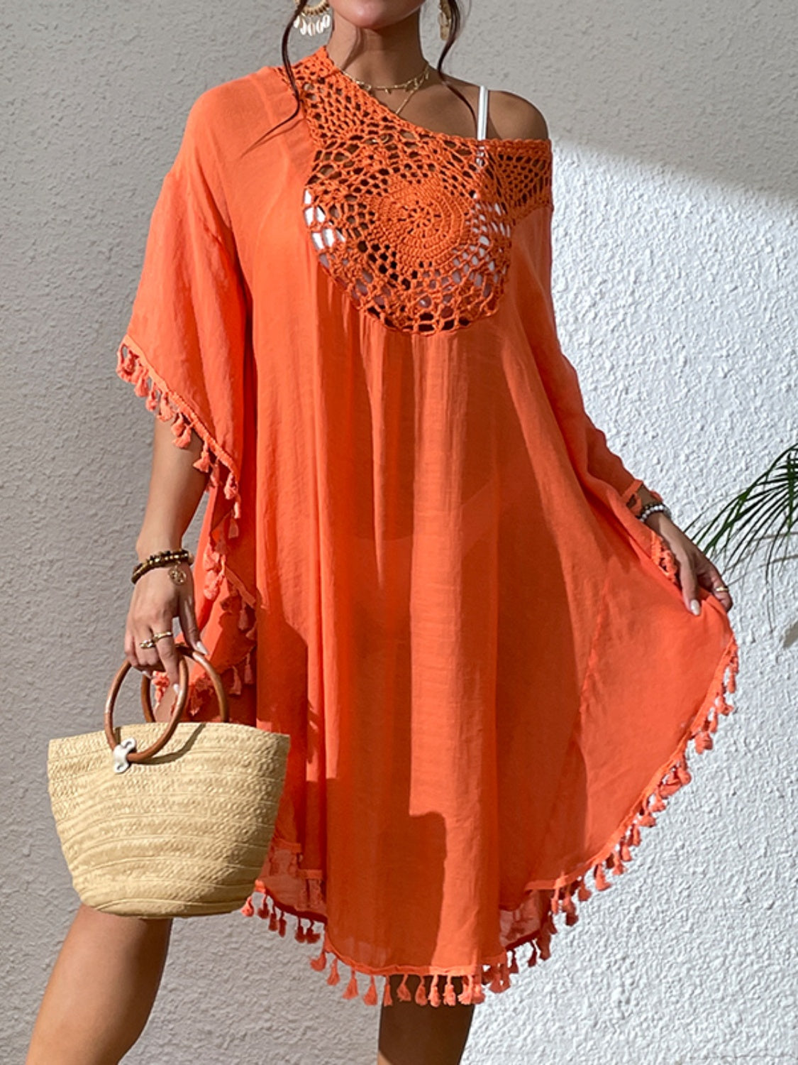 Orange kaftan dress with crochet yoke, tassel trim, and short sleeves.