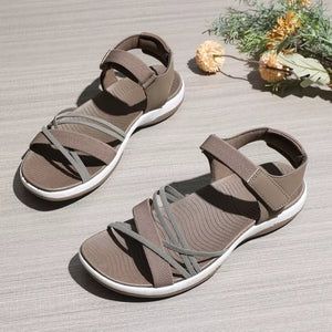 Khaki adjustable open-toe sandals with criss-cross straps and white soles.