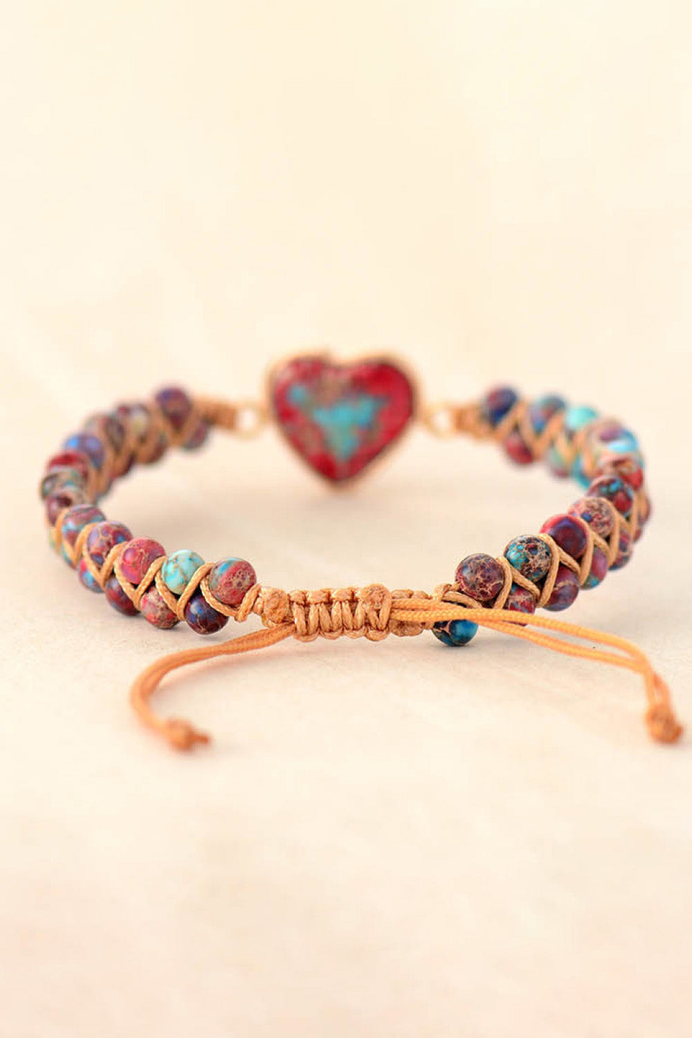 Multicolor beaded bracelet with a red and turquoise heart stone and macrame cord.