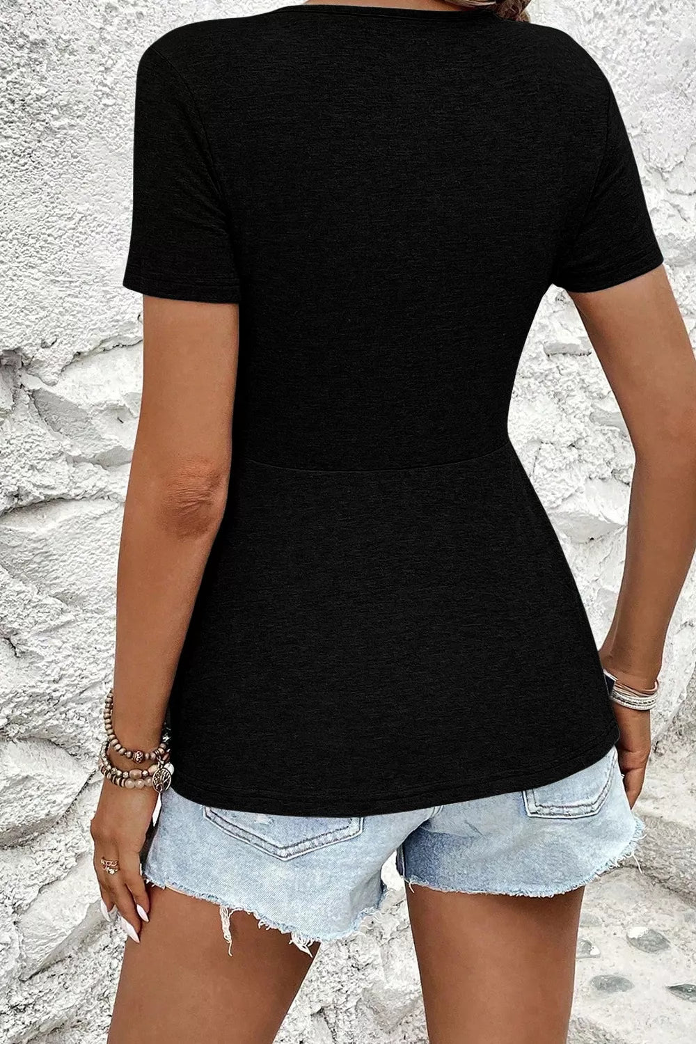 Black polyester t-shirt with short sleeves and a peplum hem, styled with denim shorts.