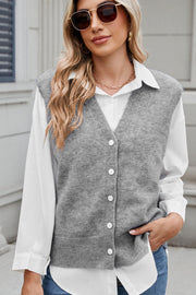 Gray button-front knit vest with V-neck and ribbed hem, styled over a white shirt.