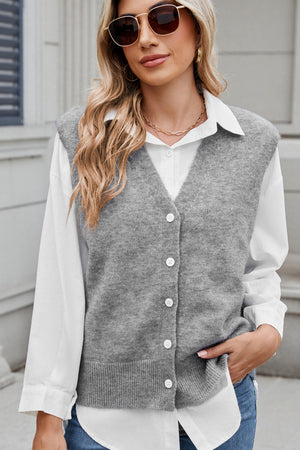 Gray button-front knit vest with V-neck and ribbed hem, styled over a white shirt.
