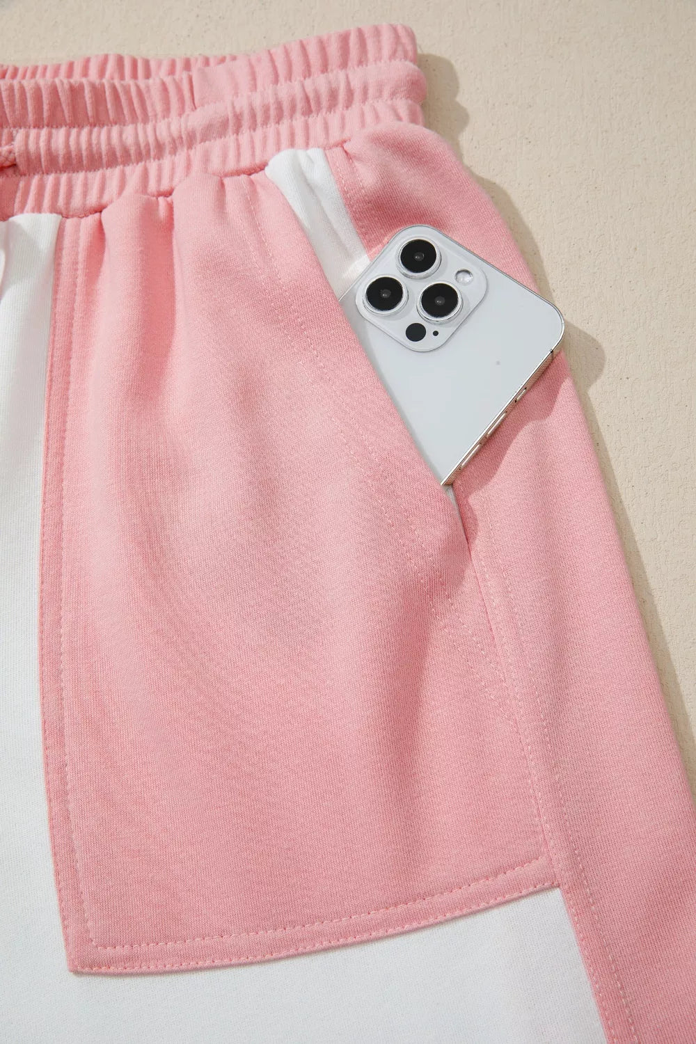 Pink and cream color block cotton lounge set shorts with side pocket holding a phone.