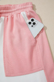 Pink and cream color block cotton lounge set shorts with side pocket holding a phone.