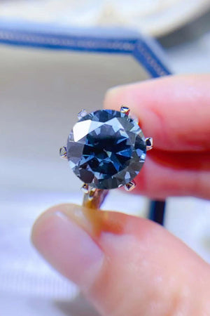 Midnight blue solitaire engagement ring with a round cut gemstone.