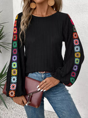 Black ribbed shirt with colorful crochet sleeve details and bell sleeves.
