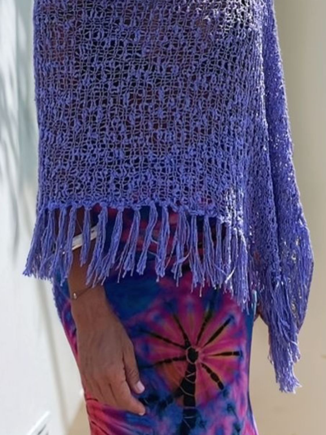 Purple open-knit acrylic poncho with fringe trim and boat neck, styled over a tie-dye dress.