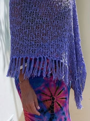 Purple open-knit acrylic poncho with fringe trim and boat neck, styled over a tie-dye dress.