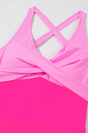 Hot pink cross-front one-piece swimsuit with criss-cross back straps and a skirted bottom.
