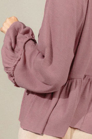 Textured ribbed peplum blouse in dusty pink with ruffled cuffs and balloon sleeves.