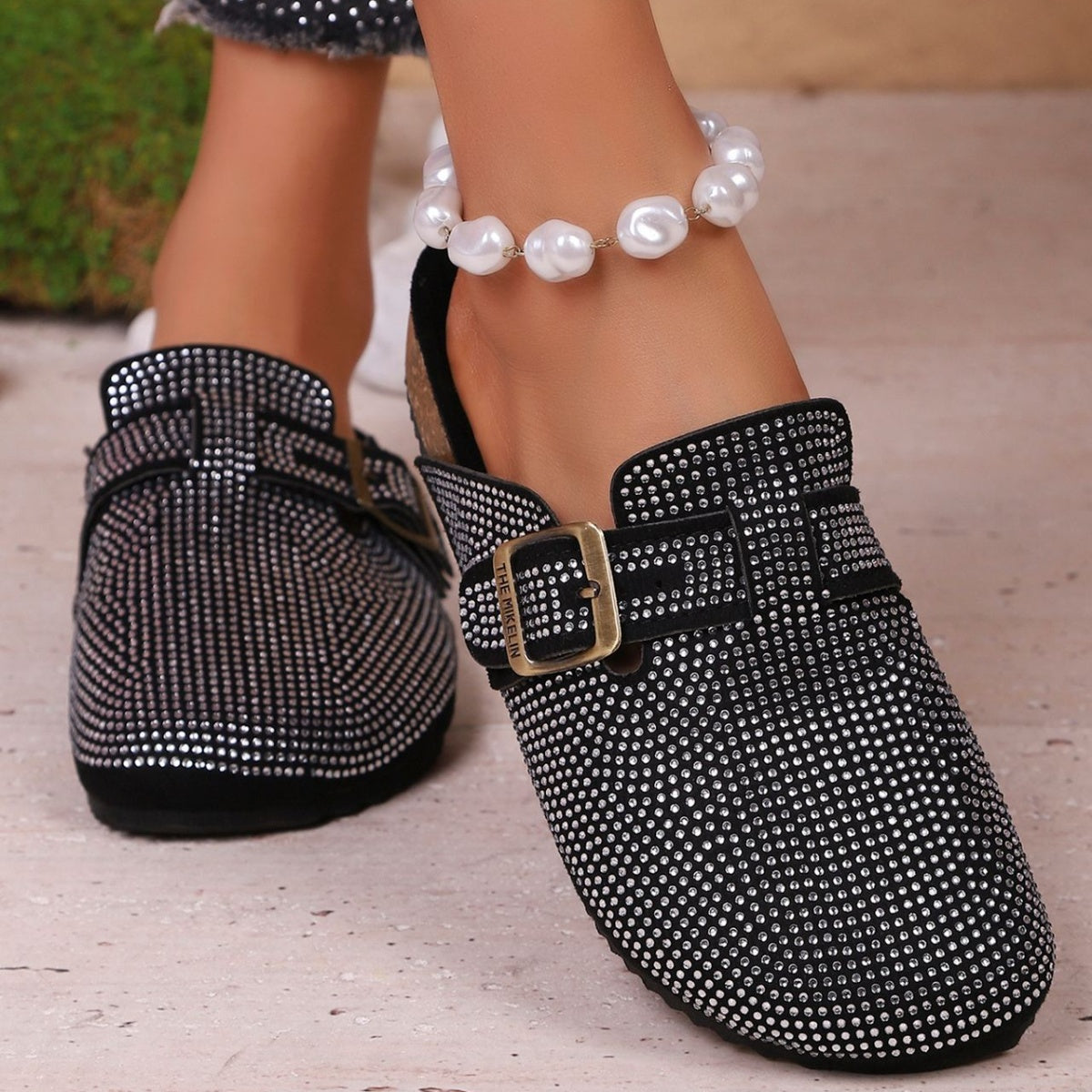 Black rhinestone buckle slip-on mules with a casual chic style.