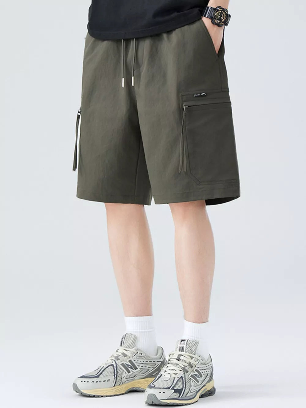 Men's military green cargo shorts with drawstring waist and zip pockets.
