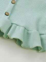 Green waffle knit tank top detail with wooden buttons and ruffled hem.