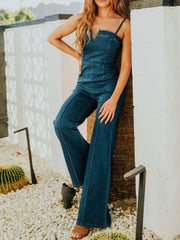 Denim jumpsuit with notched V-neck, spaghetti straps, contrast stitching, and wide legs.