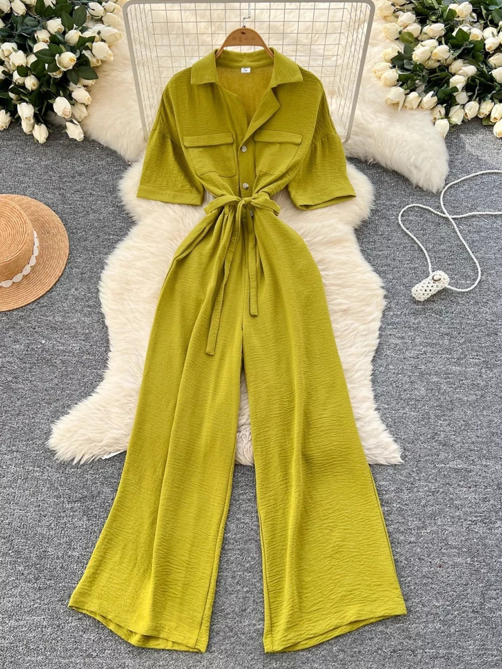 Belted wide-leg jumpsuit in green with short sleeves, collar, and button front.
