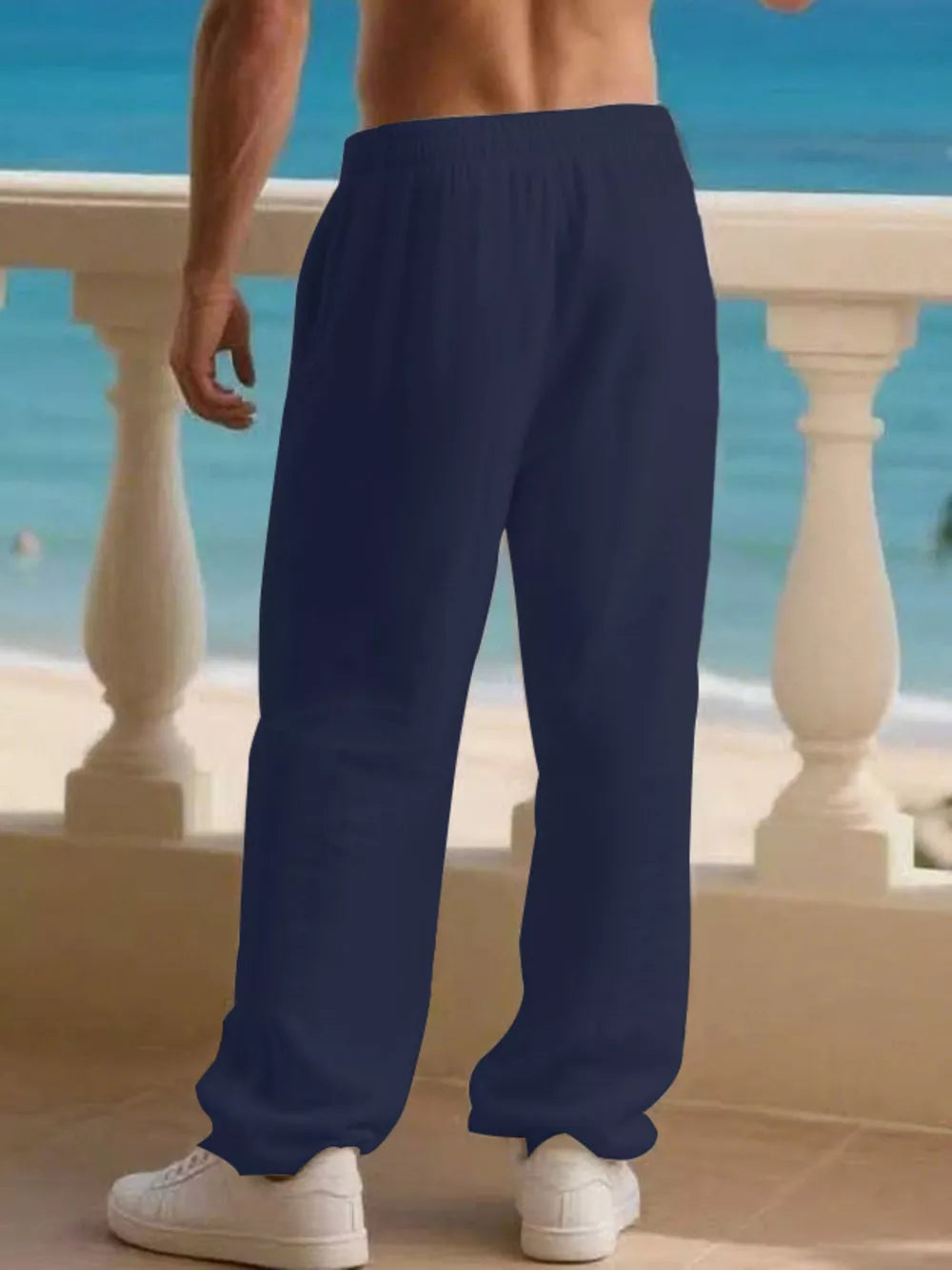 Men's navy blue linen drawstring joggers with pockets, styled with white sneakers.