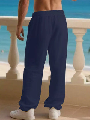 Men's navy blue linen drawstring joggers with pockets, styled with white sneakers.