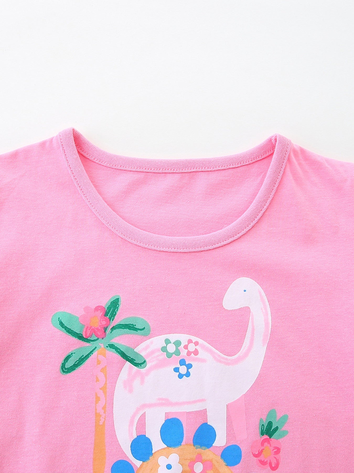 Pink cotton crew neck t-shirt with a playful dinosaur and floral print.