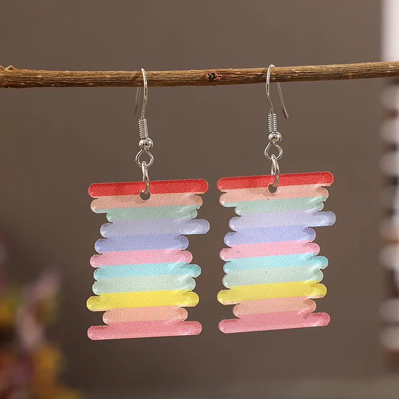 Prismatic spool acrylic earrings in multicolor, featuring layered pastel stripes.
